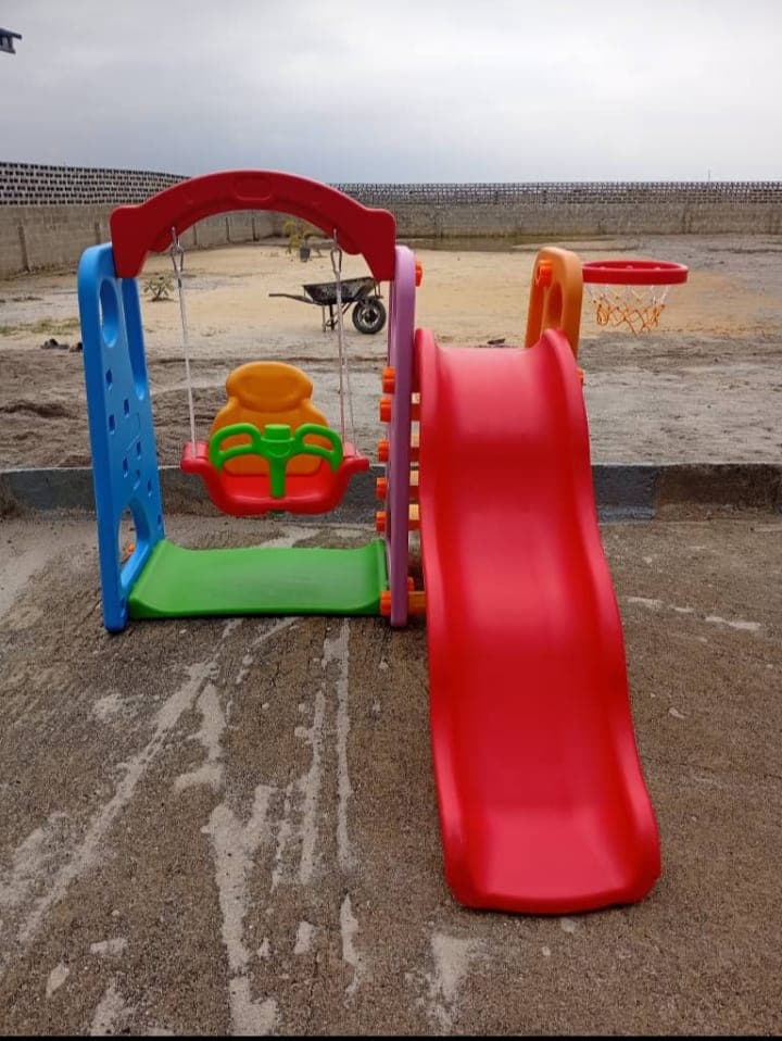 Red toddler swing, slide and basketball combo installed on a newly developed estate by Ere Ayo Mothercare Toys.