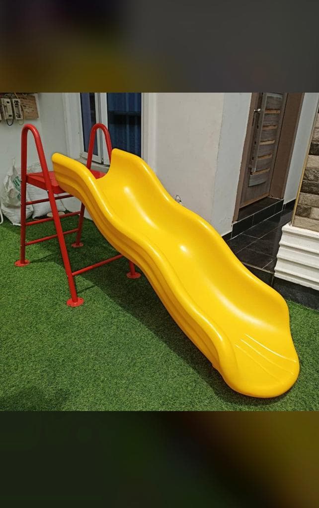 Yellow free standing wave slide with ladder installed on artificial grass by Ere Ayo Mothercare Toys.