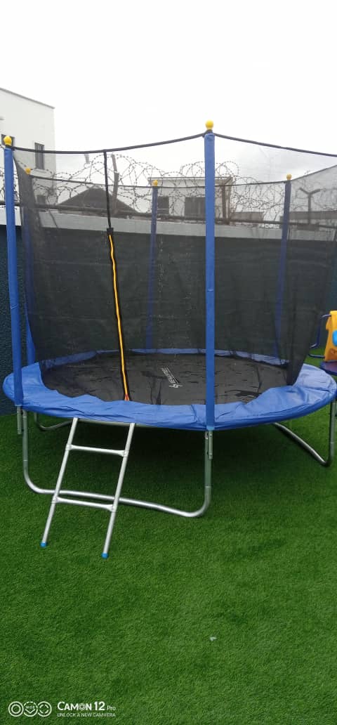 Large enclosed trampoline installed on artificial grass at a residence by Ere Ayo Mothercare Toys.