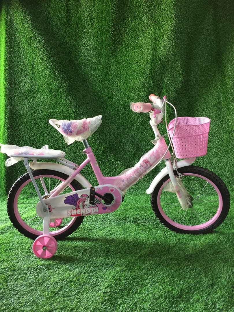 Pink girls bicycle with training wheels and a front basket.