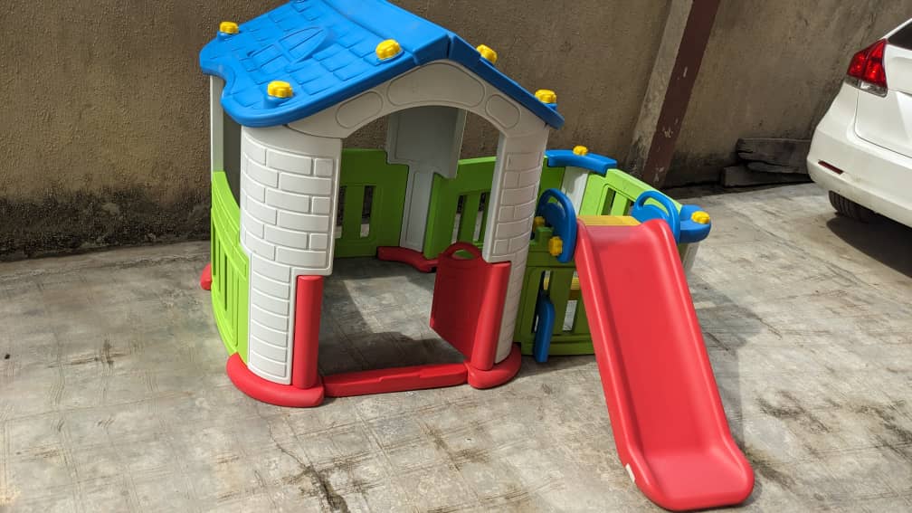 Children's cottage playhouse with an attached wave slide installed at a private home compound by Ere Ayo Mothercare Toys.